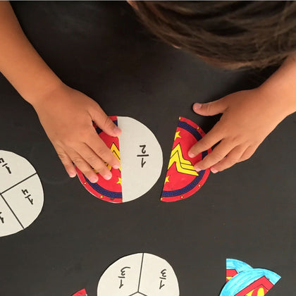 Child working on printable superhero-themed fraction puzzles as part of an educational hands-on math activity. A fun and engaging craft supporting early learning in classroom or homeschool settings.